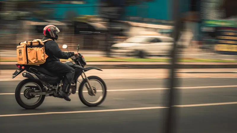 Motorbike courier riding through city traffic