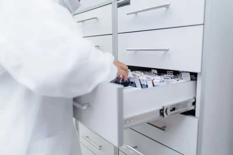 Pharmacist in a white coat opening a medicine drawer